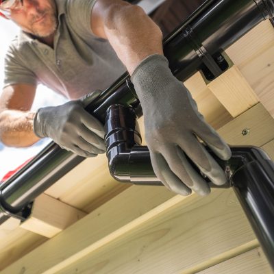 Worker Installing Gutter System on Roof